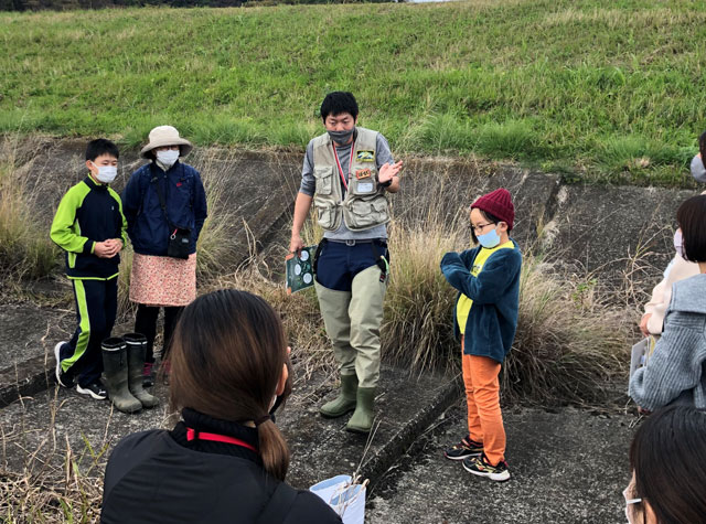 参加者の方に水生生物について説明するホールアール自然学校の馬場龍一さん